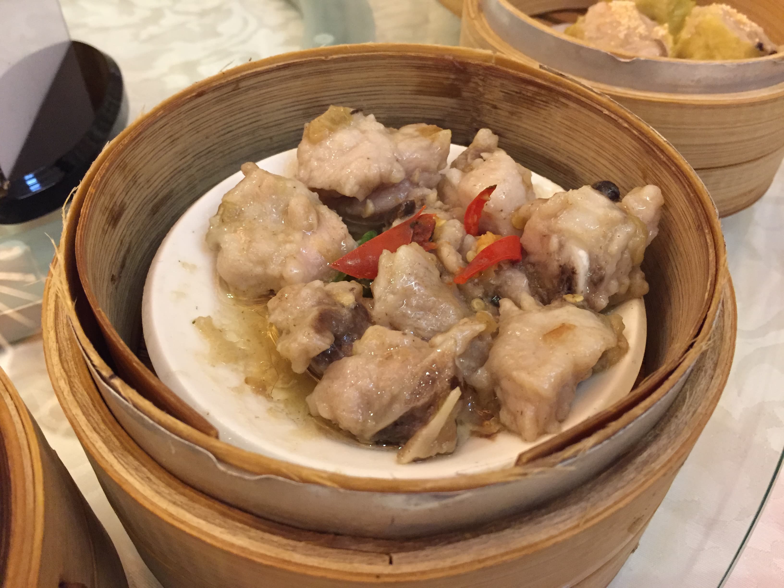 Steamed pork ribs with black beans and red pepper in a bamboo steamer