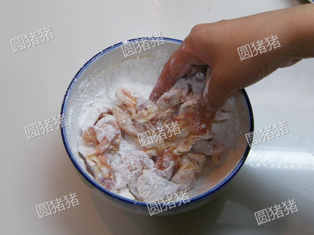 Chicken pieces being mixed with dry cornstarch in a bowl after egg-yolk seasoning.