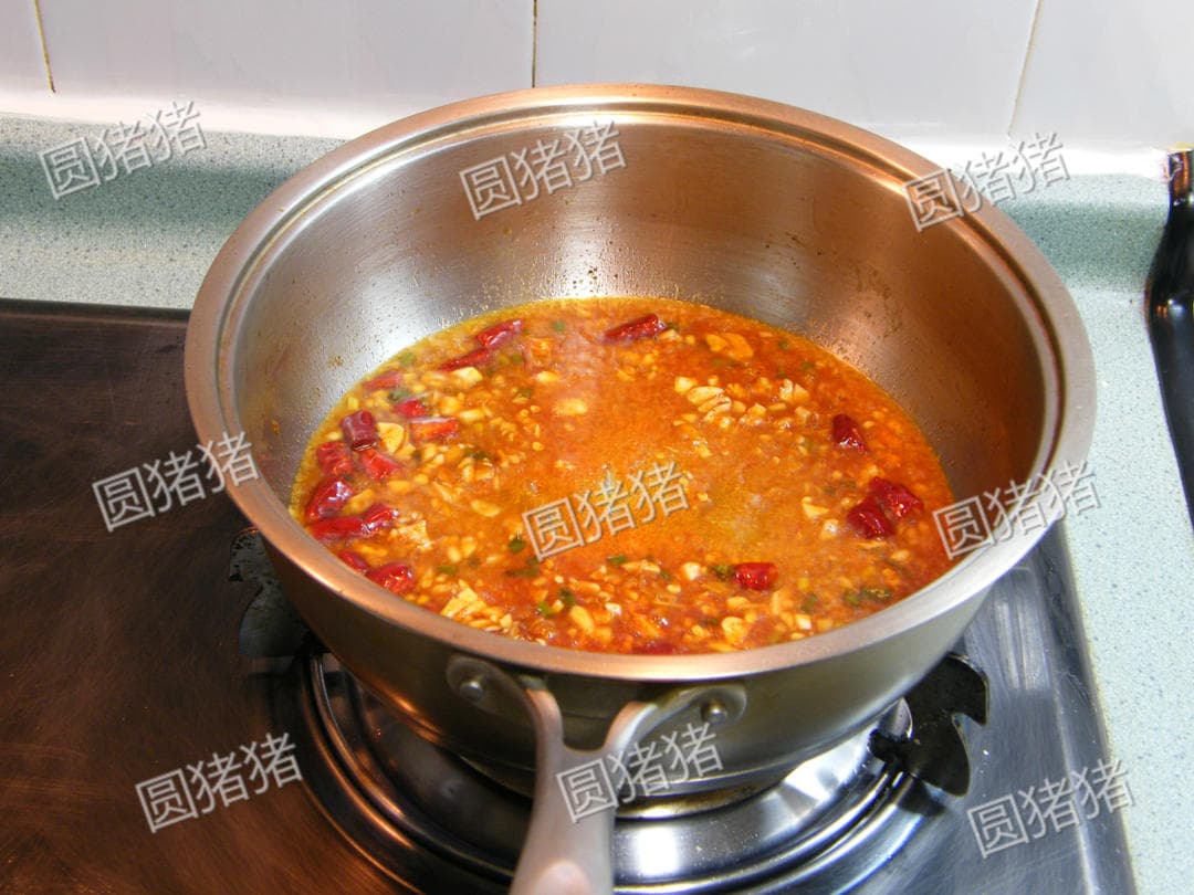 Red-brown sauce with garlic and dried chilies simmering in the skillet before the chicken is added.