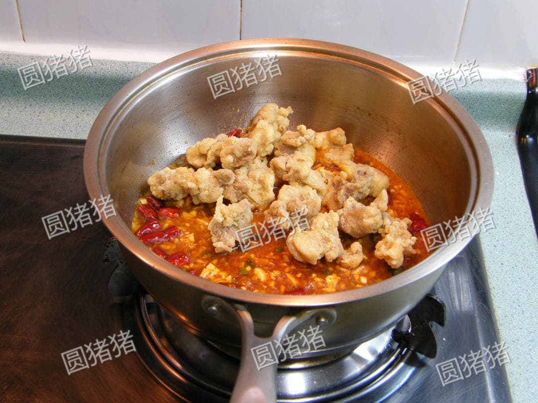 Fried chicken pieces just added on top of the thickened chili sauce, before tossing.