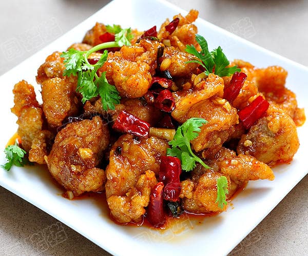 Finished General Tso's chicken with dried chilies and optional cilantro on a white square plate.