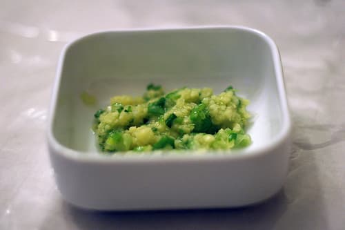 A small white dish of mashed ginger and green scallions