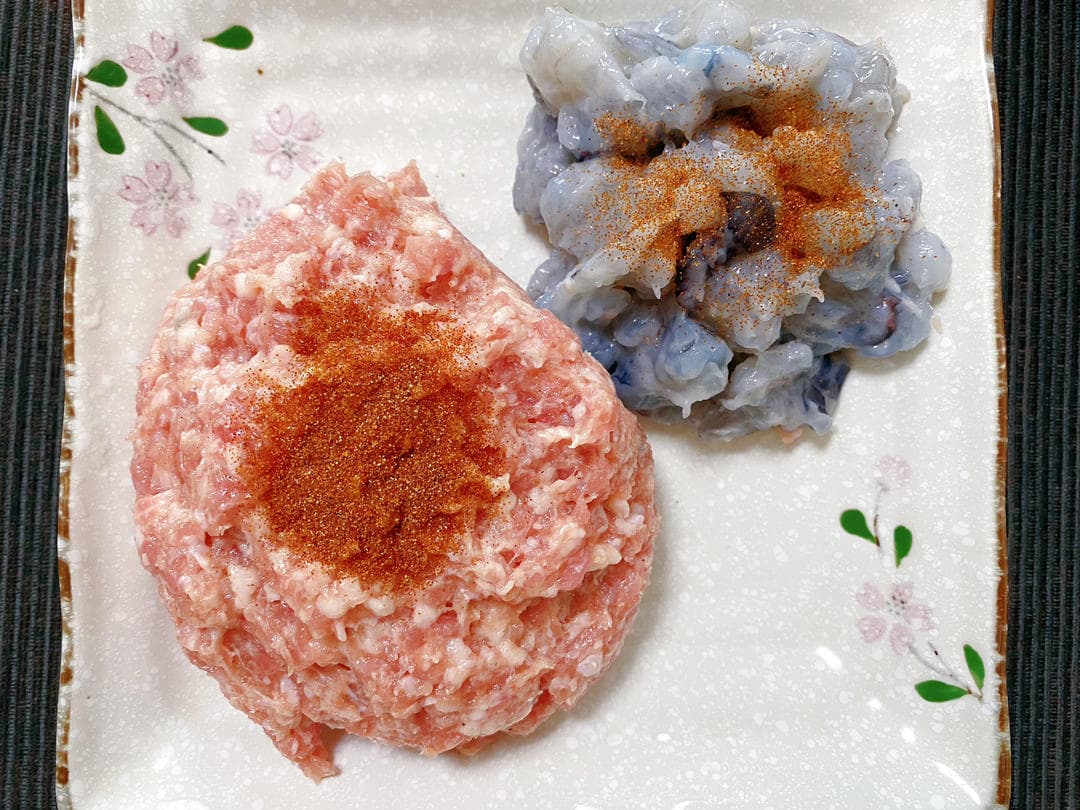 Separate portions of raw seasoned pork and raw shrimp paste with dried shrimp roe on top.