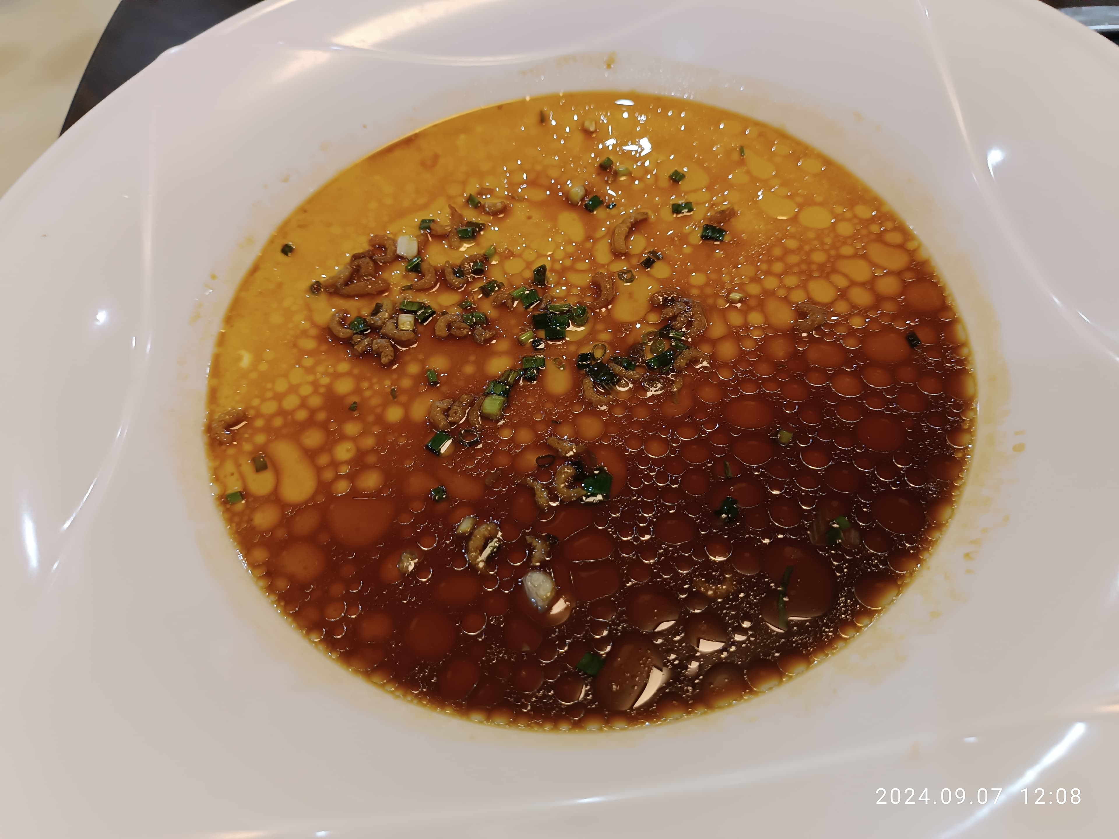 A restaurant serving of steamed egg with soy sauce and chopped aromatics
