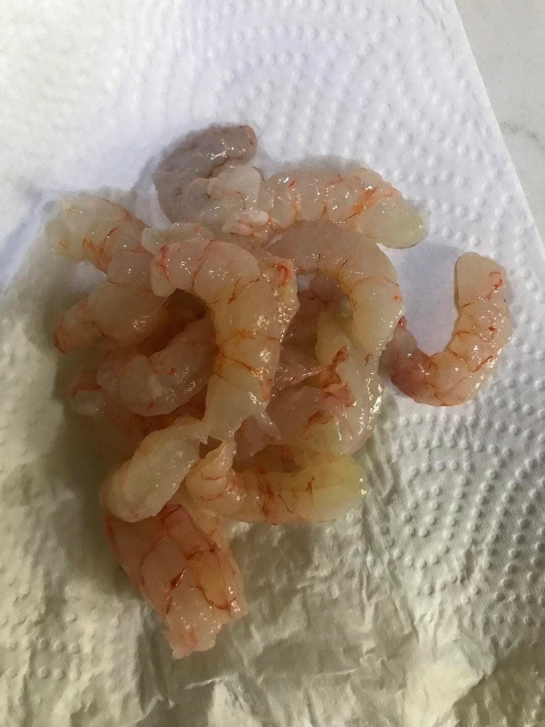 Peeled raw shrimp on kitchen paper to remove surface moisture.