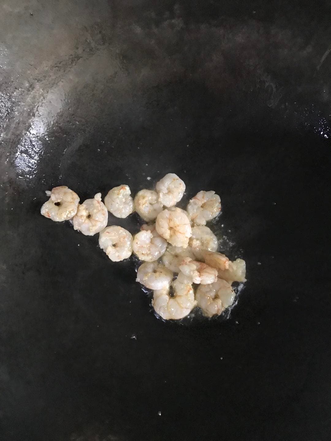 Shrimp cooking on their own in a wok before being combined with the eggs.