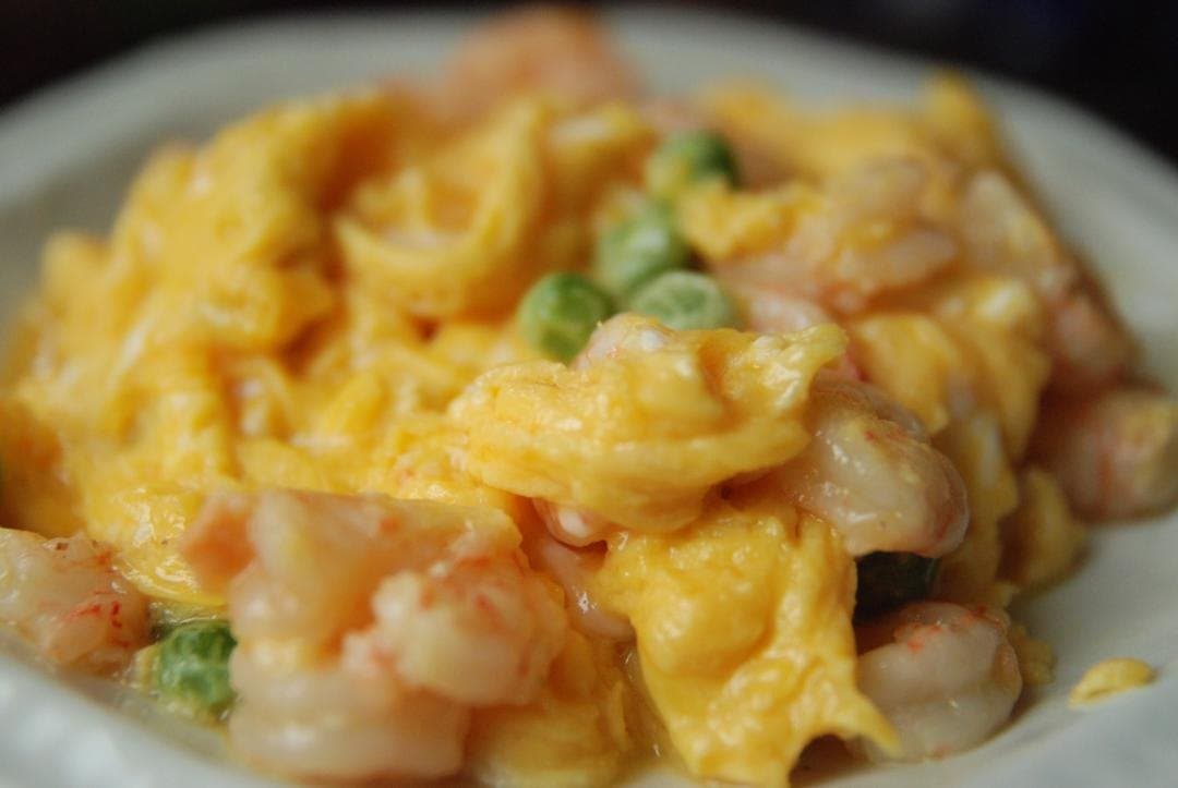 Finished shrimp and egg folds with a few green peas on a serving plate.
