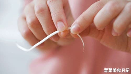 A bean sprout being trimmed before stir-frying.