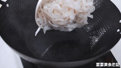 Loose wide rice noodles added to the oiled wok.