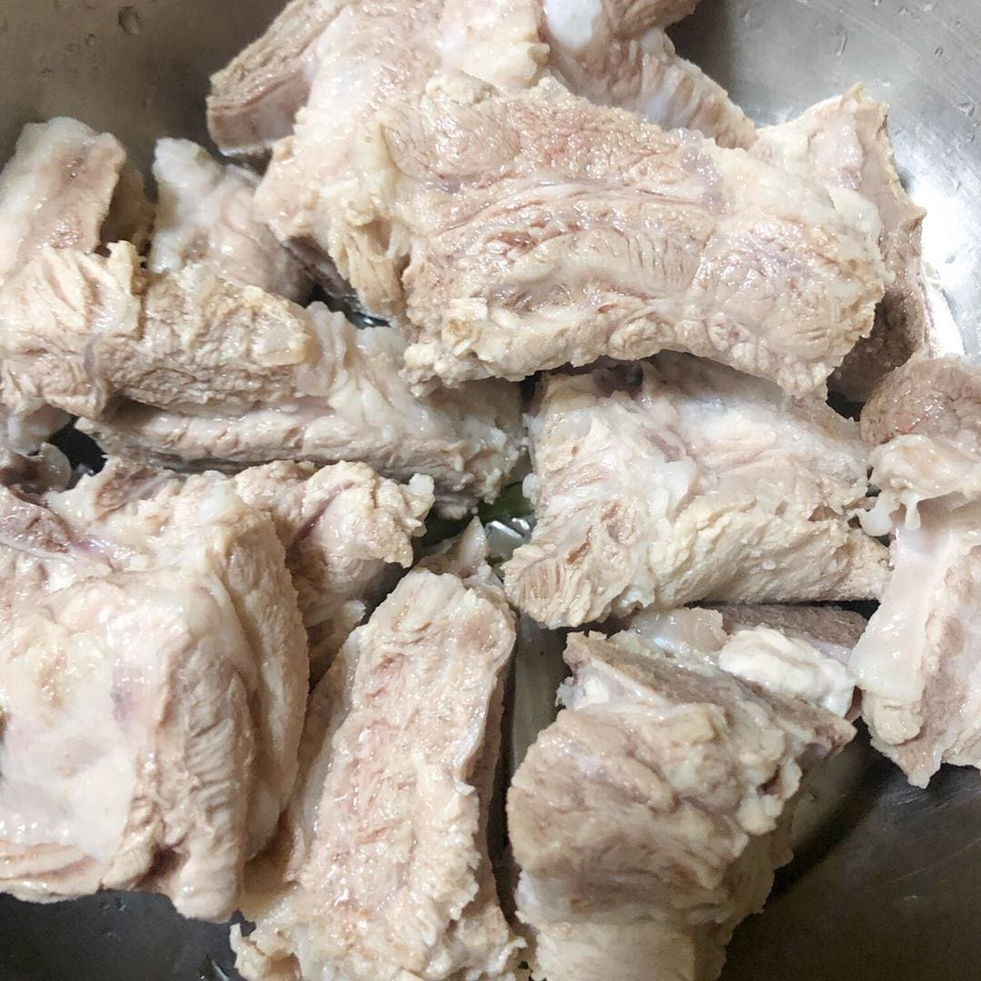 Blanched pork rib pieces drained in a bowl before they go into the soup pot.